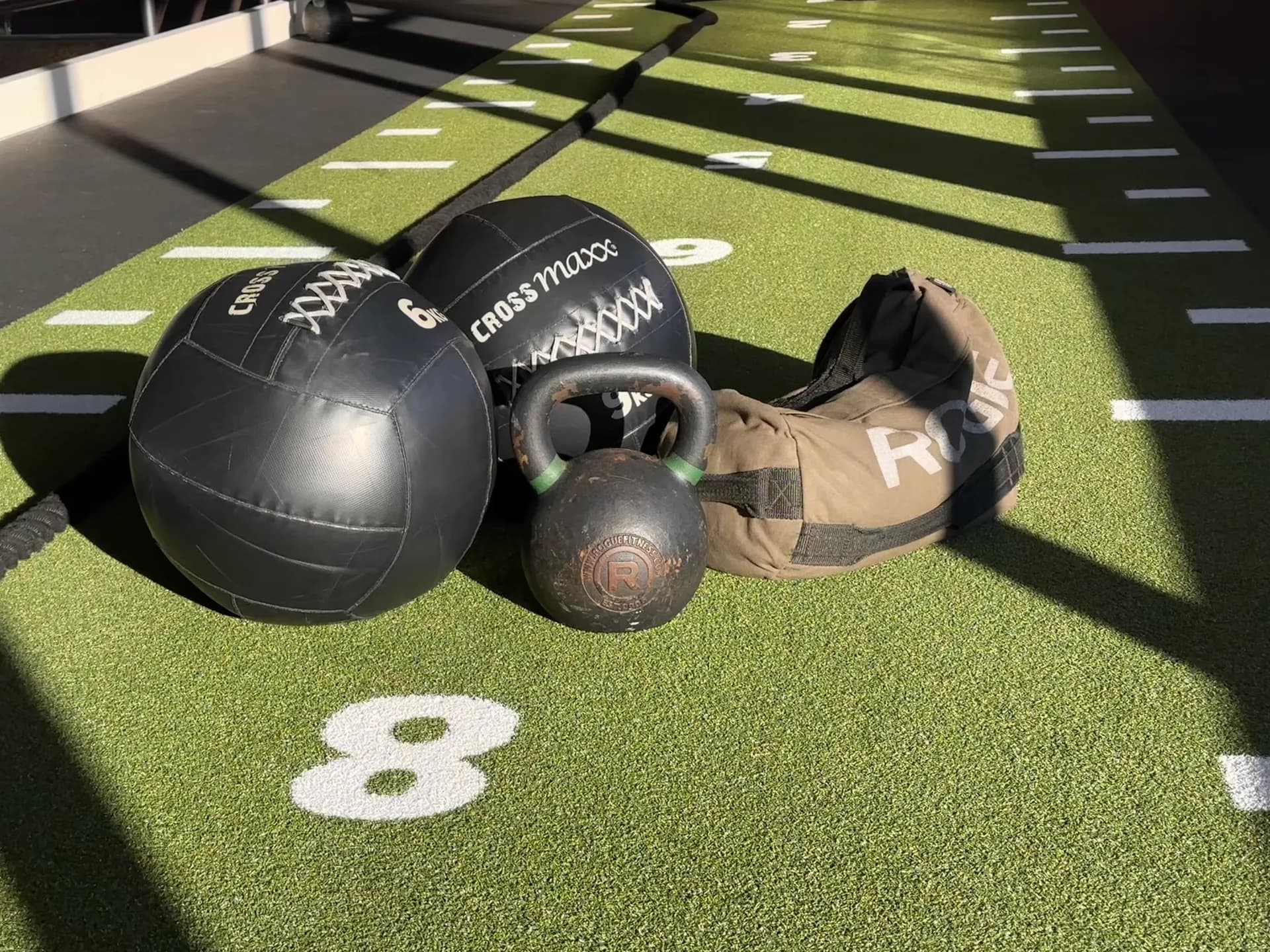 Wall balls, kettlebell en sandbag op de groene trainingsbaan